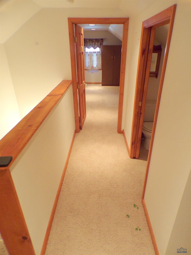 hall with lofted ceiling and light colored carpet