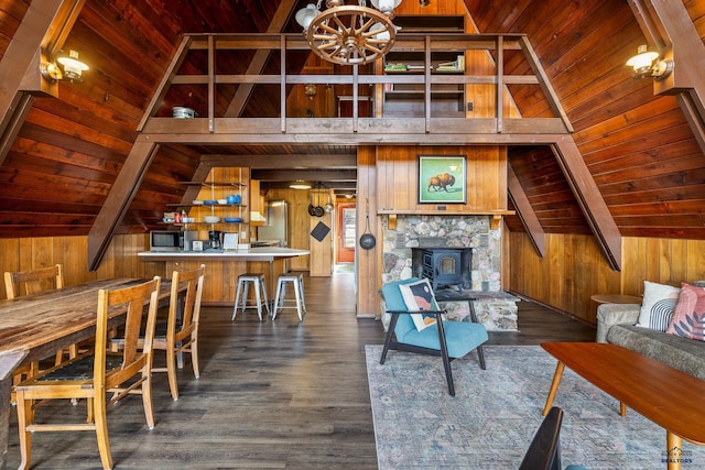 living room featuring dark wood-type flooring, lofted ceiling with beams, a wood stove, and wood walls