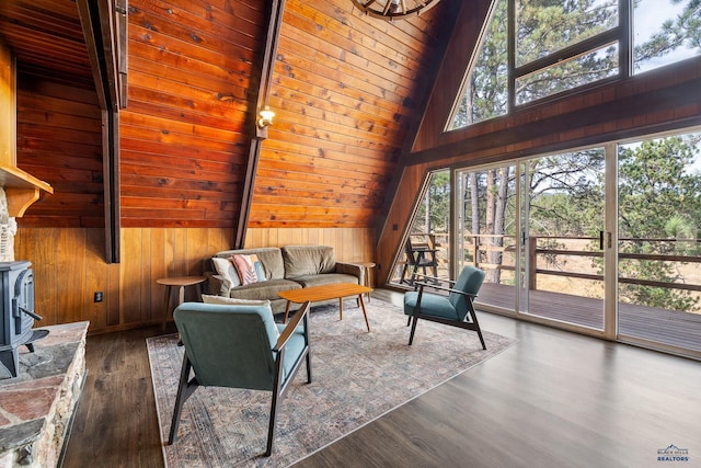 living room with vaulted ceiling with beams, wood ceiling, a wood stove, dark hardwood / wood-style flooring, and wooden walls