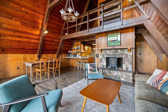 living room with vaulted ceiling with beams, a wood stove, hardwood / wood-style floors, and wood walls