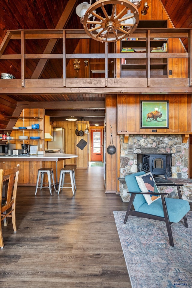 dining area with a wood stove, wooden walls, dark wood-type flooring, and wood ceiling