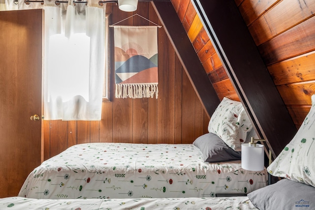 bedroom with lofted ceiling, wooden walls, and wooden ceiling