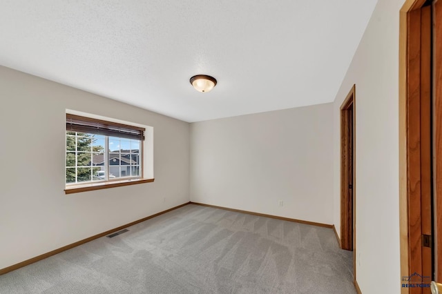 spare room with light carpet and a textured ceiling