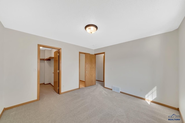 unfurnished bedroom featuring light carpet, a closet, and a spacious closet