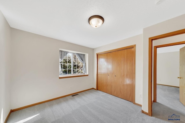 unfurnished bedroom featuring light colored carpet and a closet