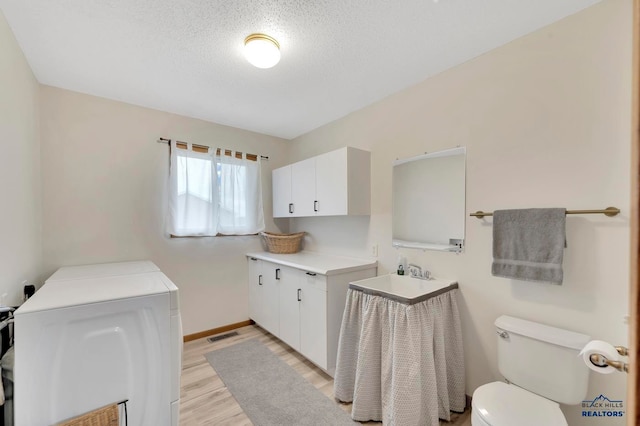 bathroom with a textured ceiling, toilet, vanity, hardwood / wood-style flooring, and washer and clothes dryer