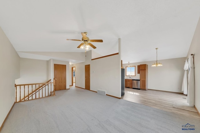 unfurnished living room with lofted ceiling, sink, ceiling fan with notable chandelier, and light wood-type flooring