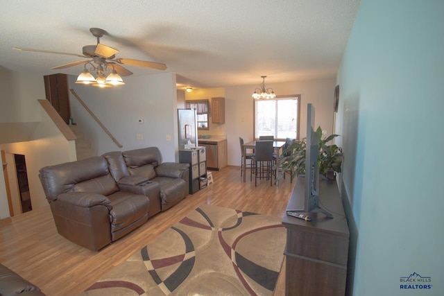 living room featuring light hardwood / wood-style flooring, a textured ceiling, and ceiling fan with notable chandelier