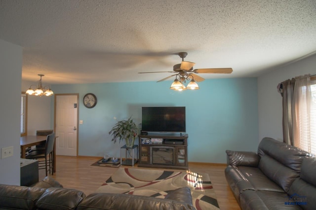 living room with light hardwood / wood-style floors, a textured ceiling, and ceiling fan with notable chandelier