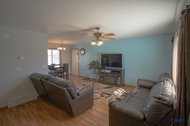 living room featuring light hardwood / wood-style floors, a textured ceiling, and ceiling fan with notable chandelier