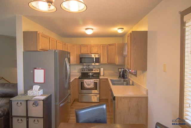 kitchen with appliances with stainless steel finishes, a textured ceiling, sink, and light brown cabinetry