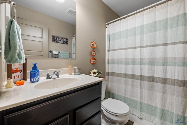 bathroom featuring vanity, walk in shower, and toilet