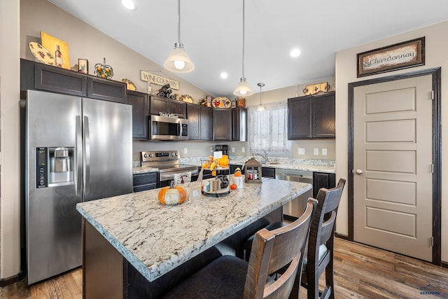 kitchen with a kitchen island, hardwood / wood-style floors, hanging light fixtures, stainless steel appliances, and vaulted ceiling