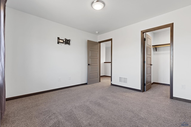 unfurnished bedroom featuring a spacious closet, a closet, and carpet floors