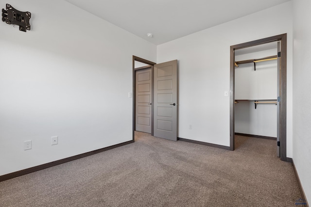 unfurnished bedroom with a spacious closet, carpet floors, and a closet