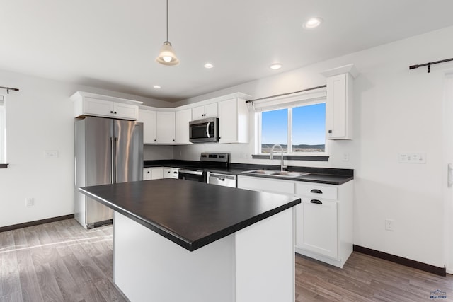 kitchen with stainless steel appliances, sink, decorative light fixtures, light hardwood / wood-style flooring, and a center island