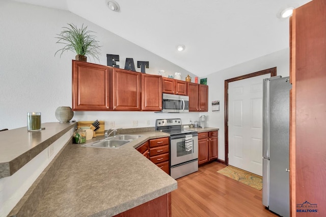 kitchen featuring sink, light hardwood / wood-style floors, appliances with stainless steel finishes, and vaulted ceiling