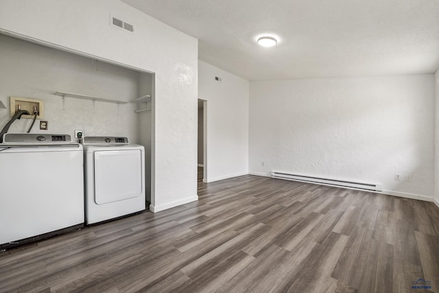 washroom with a textured ceiling, a baseboard heating unit, washer and dryer, and hardwood / wood-style flooring