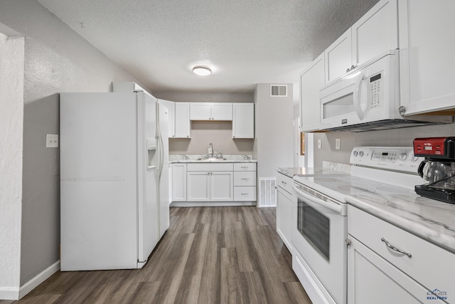 kitchen with white appliances, light stone countertops, a textured ceiling, white cabinets, and dark wood-type flooring