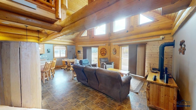 living area with a healthy amount of sunlight, stone finish floor, and beamed ceiling