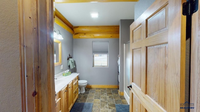 bathroom with stone finish floor, vanity, toilet, and baseboards