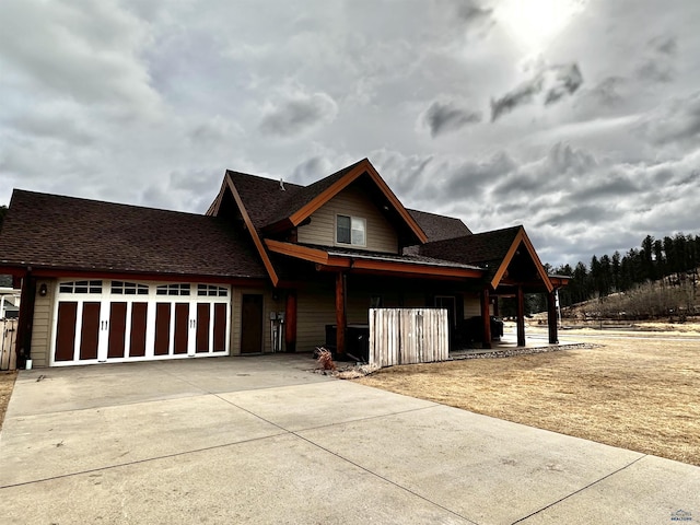 view of front of property with a garage, roof with shingles, and driveway