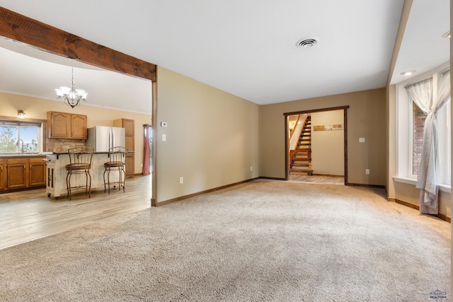 unfurnished living room featuring light hardwood / wood-style floors, an inviting chandelier, and sink