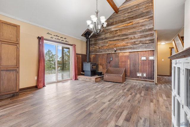 unfurnished room with light hardwood / wood-style floors, a wood stove, ornamental molding, and wooden walls