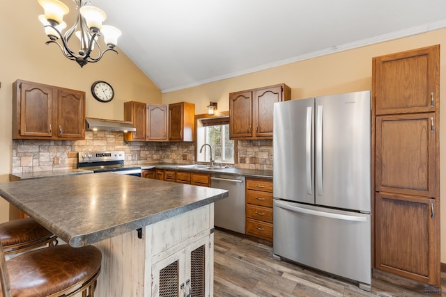 kitchen featuring lofted ceiling, a kitchen breakfast bar, stainless steel appliances, decorative light fixtures, and dark hardwood / wood-style flooring