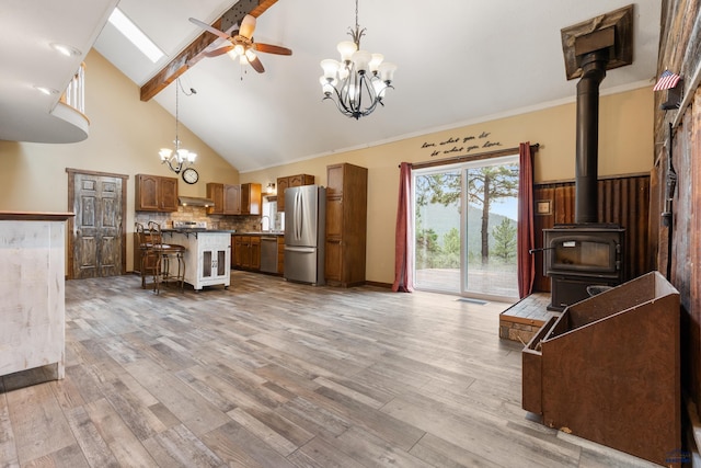 kitchen with appliances with stainless steel finishes, a kitchen bar, light wood-type flooring, and a kitchen island