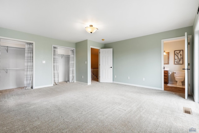 unfurnished bedroom featuring ensuite bathroom and carpet floors