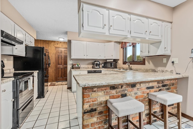 kitchen featuring black appliances, sink, kitchen peninsula, a kitchen breakfast bar, and white cabinetry