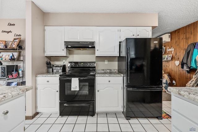 kitchen featuring black appliances, light tile patterned flooring, white cabinetry, wooden walls, and extractor fan