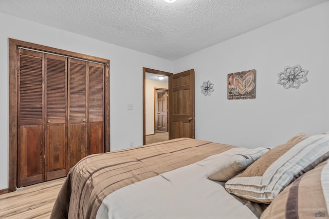 bedroom featuring light hardwood / wood-style floors, a textured ceiling, and a closet