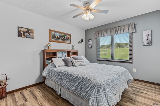 bedroom with hardwood / wood-style floors, a textured ceiling, and ceiling fan