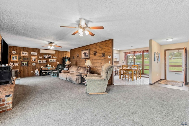 unfurnished living room with wooden walls, light colored carpet, a textured ceiling, and ceiling fan