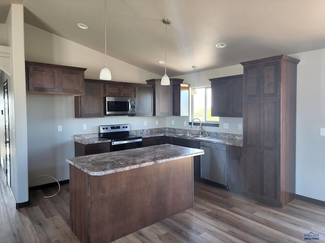 kitchen with sink, appliances with stainless steel finishes, dark hardwood / wood-style flooring, a kitchen island, and pendant lighting