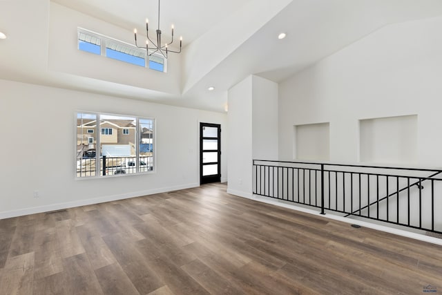 entrance foyer with a towering ceiling, a notable chandelier, and hardwood / wood-style flooring