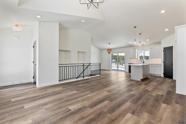 unfurnished living room with high vaulted ceiling, hardwood / wood-style flooring, a chandelier, and sink