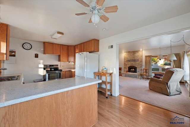 kitchen with light hardwood / wood-style floors, electric stove, sink, white fridge, and decorative light fixtures