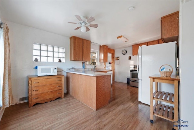 kitchen featuring light wood-type flooring, white appliances, sink, kitchen peninsula, and ceiling fan