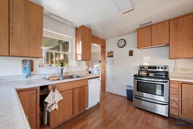 kitchen featuring stainless steel range with electric cooktop, white dishwasher, sink, hardwood / wood-style flooring, and independent washer and dryer