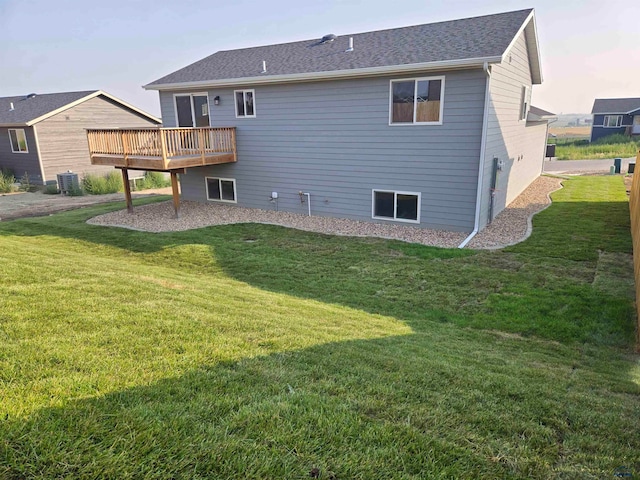 back house at dusk featuring a wooden deck, a lawn, and central AC