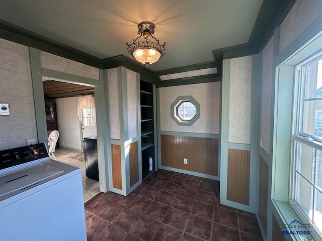 laundry room with dark tile patterned floors, washer / dryer, crown molding, built in features, and wooden walls