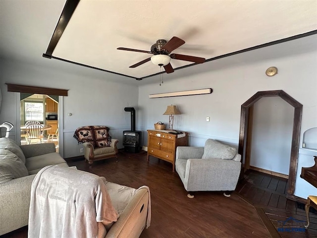 living room with dark wood-type flooring, a wood stove, and ceiling fan