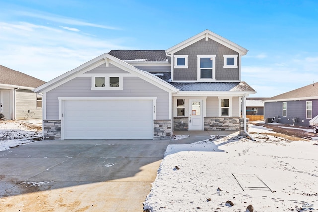 view of front facade with a porch, stone siding, driveway, a garage, and central AC unit