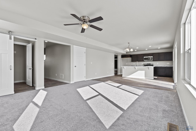 unfurnished living room featuring carpet flooring, recessed lighting, a ceiling fan, a chandelier, and baseboards