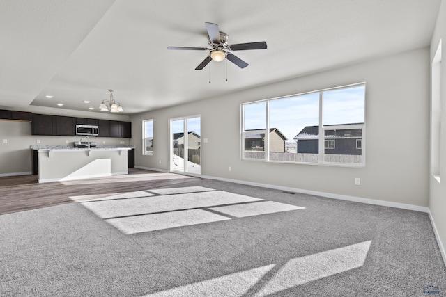 unfurnished living room with a chandelier, carpet floors, baseboards, recessed lighting, and ceiling fan