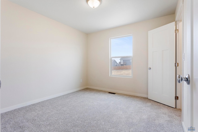 spare room with light carpet, visible vents, and baseboards