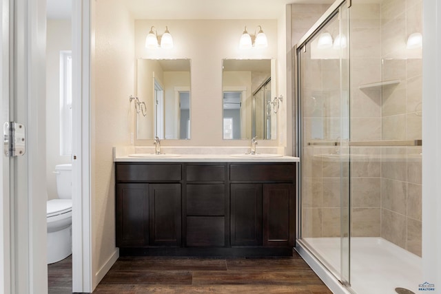 full bath with a sink, a shower stall, toilet, and wood finished floors